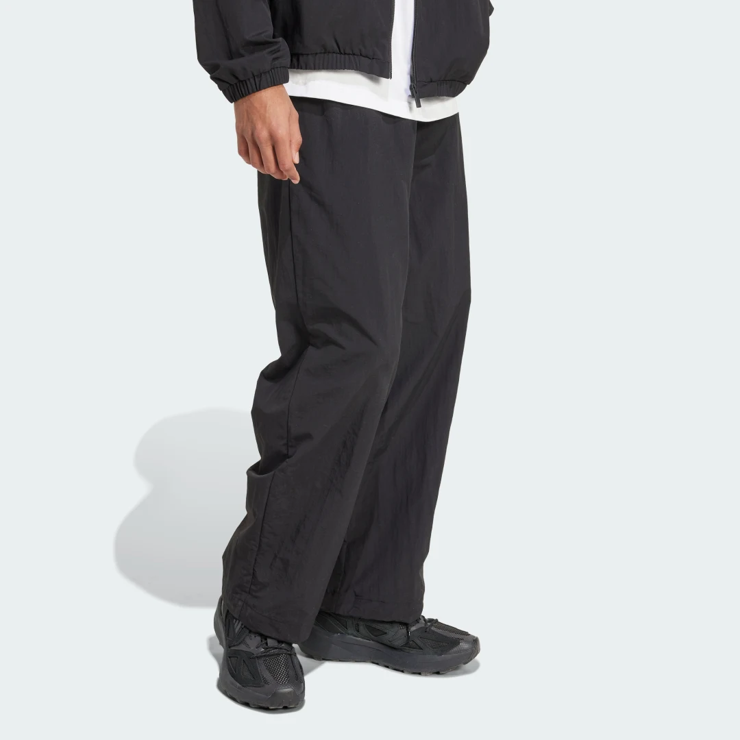 Detalle de Pantalón técnico Essential de Adidas (negro) con logotipo pequeño y dobladillo abierto