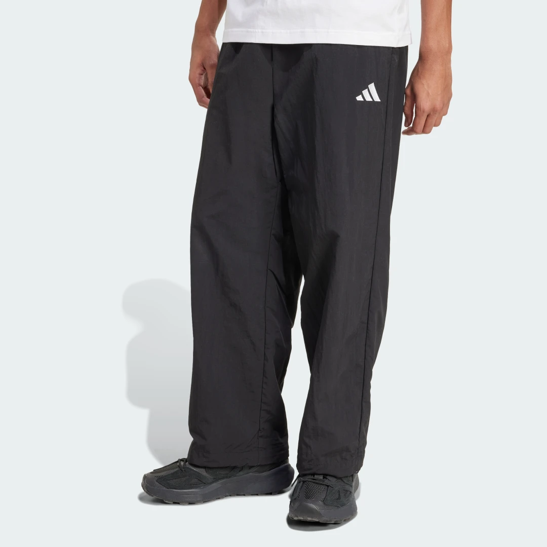 Detalle de Pantalón técnico Essential de Adidas (negro) con logotipo pequeño y dobladillo abierto
